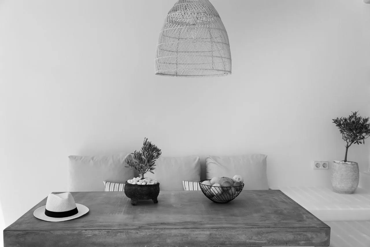 The interior of Calma Suite: cement table, olive tree and rattan light, Milos